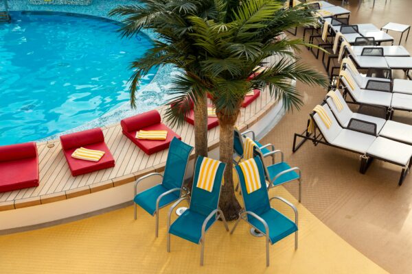 Cruise ship pool deck with palm tree and lounge chairs - photo by travelpricewatch on Unsplash