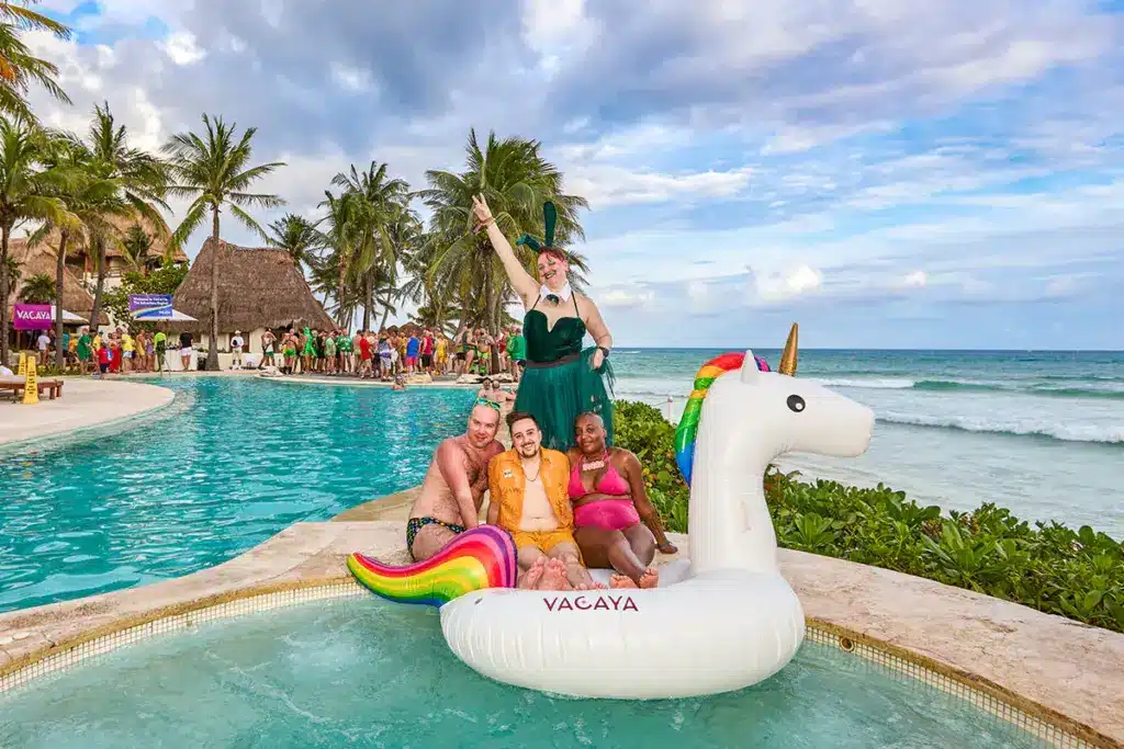 VACAYA guests posing on a unicorn pool float beside the Caribbean Sea