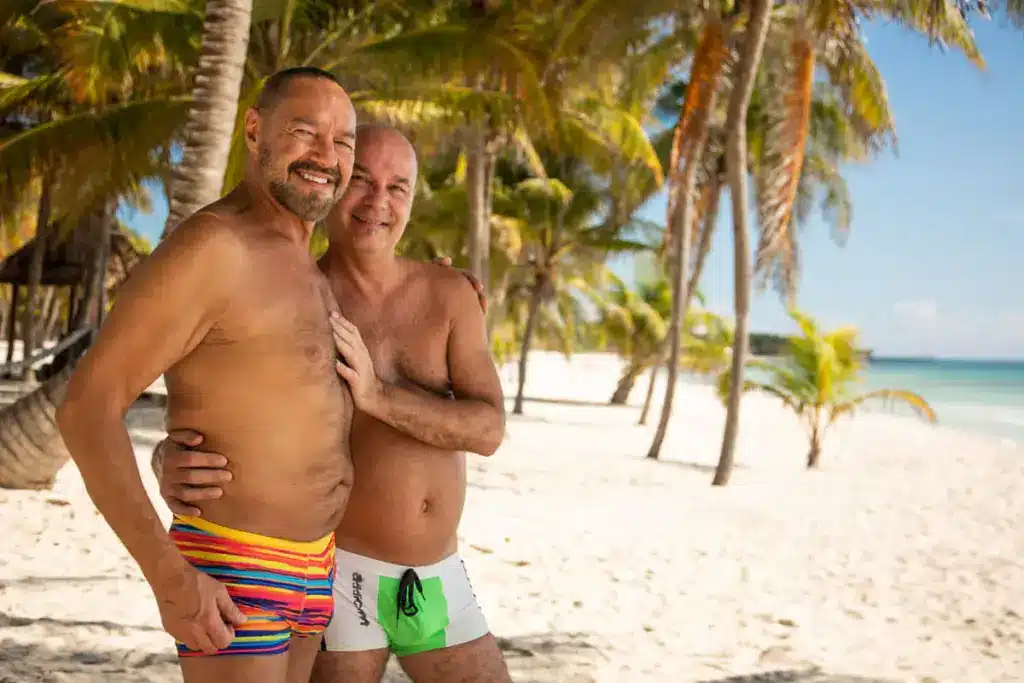 Two VACAYA travelers embracing on a palm-lined Caribbean beach